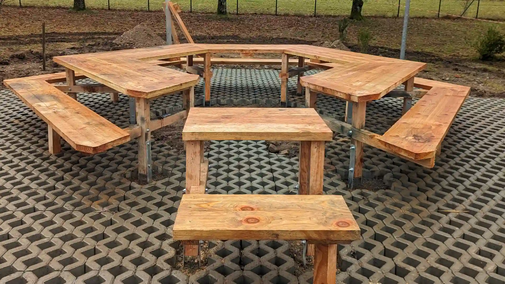 Custom octagonal wooden outdoor seating with interconnected benches on eco-friendly permeable paving, ideal for landscape design and communal spaces.